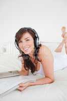 Beautiful female with headphones reading a magazine while lying