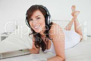 Lovely female with headphones reading a magazine while lying