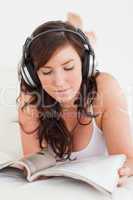 Attractive female with headphones reading a magazine while lying
