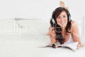 Pretty female with headphones reading a magazine while lying