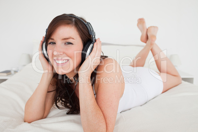 Charming female with headphones lying