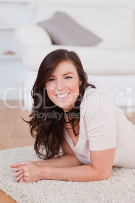 Good looking brunette woman posing while lying on a carpet