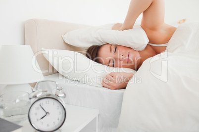 Pretty brunette woman awaking with a clock while lying