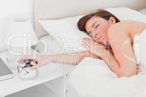 Pretty brunette female awaking with a clock while lying