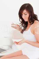 Beautiful brunette female taking some pills while sitting