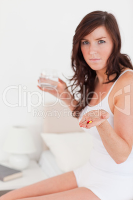 Good looking brunette female taking some pills while sitting