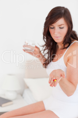 Pretty brunette female taking some pills while sitting