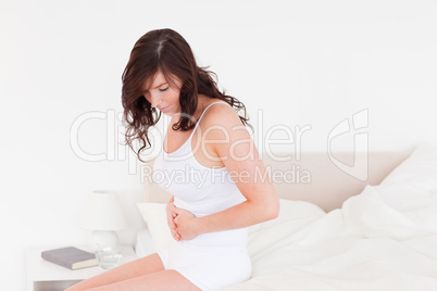Attractive brunette woman having a stomach ache while sitting