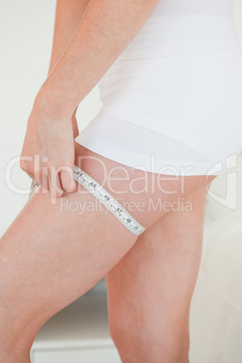Woman measuring her hip with a tape measure while standing