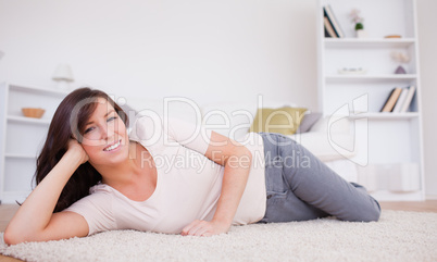 Gorgeous brunette woman posing while lying on a carpet