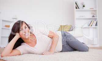 Gorgeous brunette woman posing while lying on a carpet