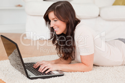 Attractive brunette woman relaxing with her laptop while lying o