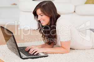 Attractive brunette woman relaxing with her laptop while lying o