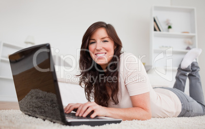 Beautiful brunette woman relaxing with her laptop while lying on