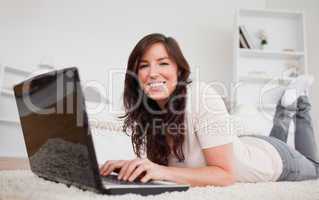 Beautiful brunette woman relaxing with her laptop while lying on