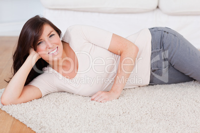 Beautiful smiling woman posing while lying on a carpet