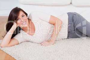 Beautiful smiling woman posing while lying on a carpet