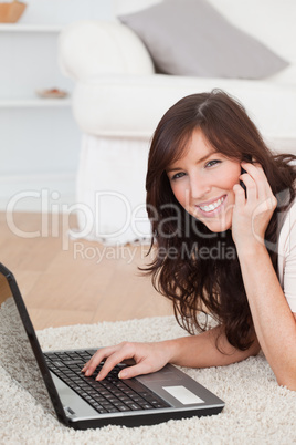 Cute brunette woman on the phone while relaxing with her laptop