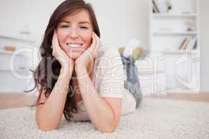 Beautiful brunette female posing while lying on a carpet