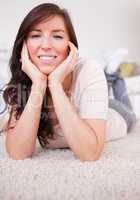 Good looking brunette female posing while lying on a carpet