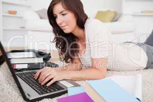 Young brunette woman relaxing with her laptop while lying on a c