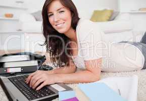 Young beautiful woman relaxing with her laptop while lying on a