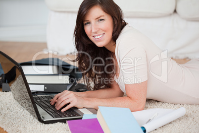 Young charming woman relaxing with her laptop while lying on a c