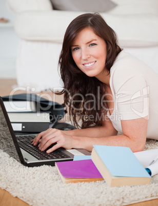 Young pretty woman relaxing with her laptop while lying on a car