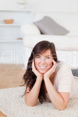 Attractive brunette female posing while lying on a carpet