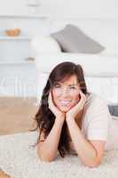 Attractive brunette female posing while lying on a carpet