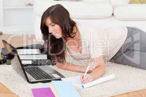 Young beautiful woman relaxing with her laptop while writing on