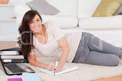 Young cute woman relaxing with her laptop while writing on a not
