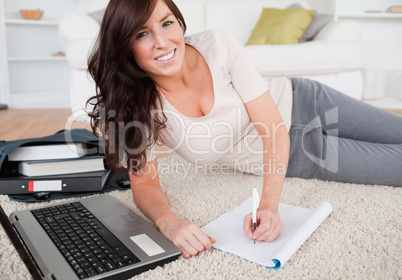 Young pretty woman relaxing with her laptop while writing on a n
