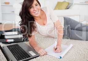 Young pretty woman relaxing with her laptop while writing on a n