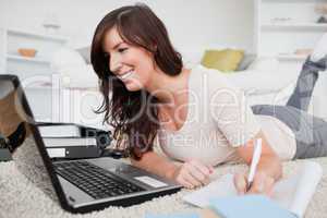 Young charming woman relaxing with her laptop while writing on a