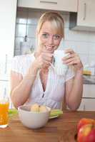 young blond woman at a table with breakfast