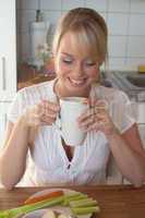 young blond woman laughs with a cup of tea