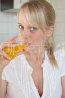 young blond woman drinks juice out of a glass