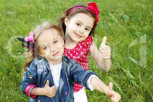 Two little girls friends. Thumbs up