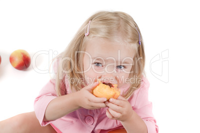 Little girl eating peach in studio