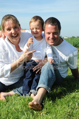 Junge Eltern mit Kleinkind im Sommer auf der Wiese