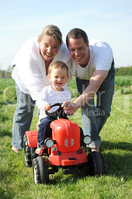 Eltern und Kleinkind mir rotem Traktor