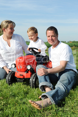 Eltern und Kleinkind mir rotem Traktor