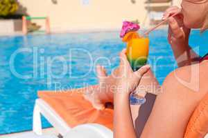 Woman hand drinking cocktail near swimming pool