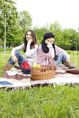 Mother and daughter talk on the phone in the park