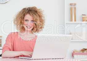 Beautiful blonde female relaxing with her laptop while sitting i