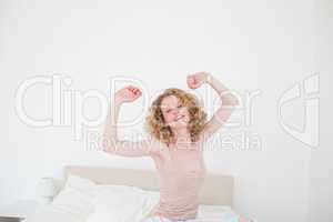 Pretty blonde female stretching in her bedroom