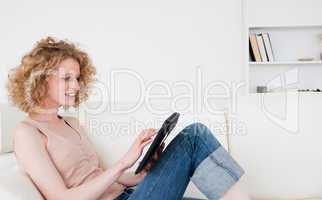 Charming blonde woman relaxing with her tablet while sitting on