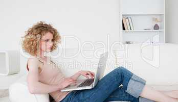Beautiful blonde woman relaxing with her laptop while sitting on