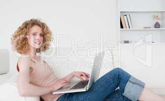 Attractive blonde woman relaxing with her laptop while sitting o